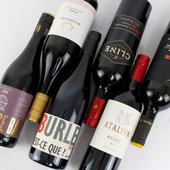 Collection of wine bottles with various labels on a light gray background