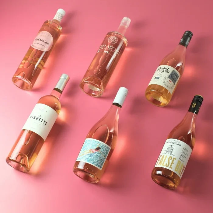 Six bottles of rosé wine arranged on a pink background